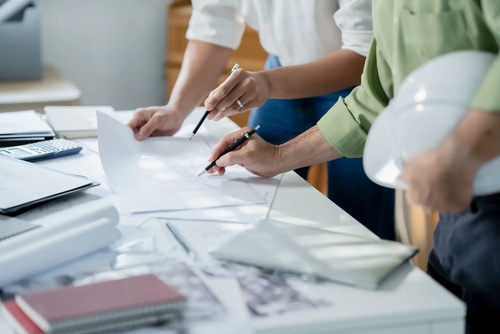 Baustellenkoordination und Projektmanagement Team bei der Baustellenkoordination mit Plänen und Dokumenten für professionelles Projektmanagement