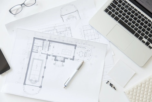 Detaillierte Ausführungsplanung Architekturpläne und Grundrisse auf einem Schreibtisch mit Laptop, Brille und Stift für detaillierte Ausführungsplanung